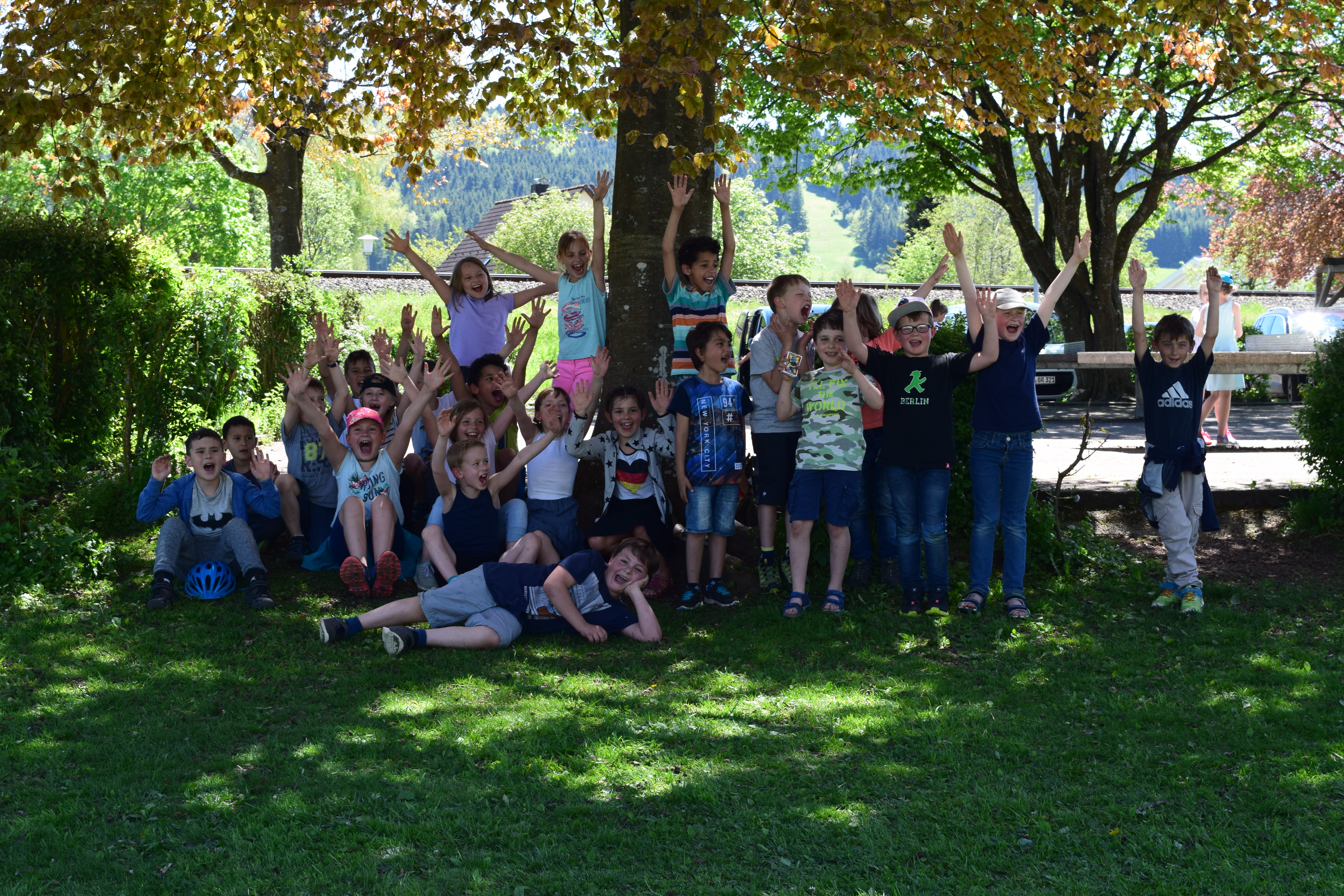 Bild von Schülern aus dem Ganztag der Anton-Braun-Grundschule im Schulgarten vor einem Baum.